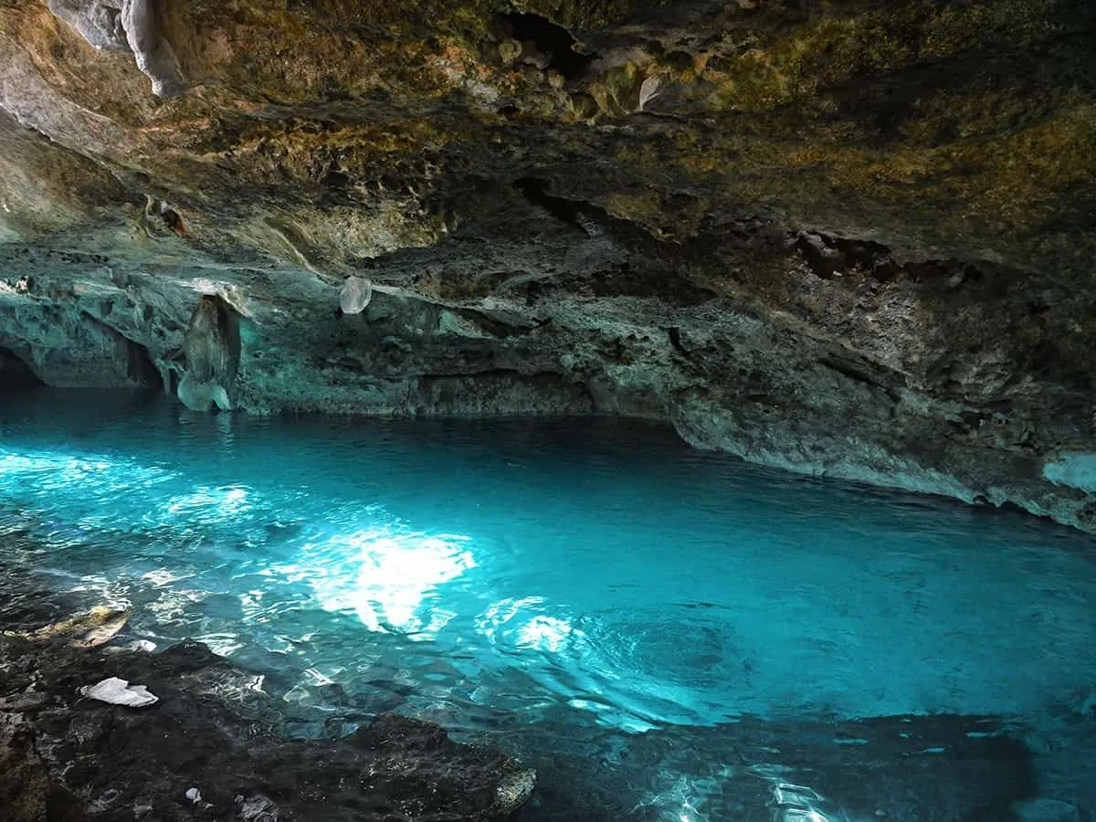 Bright turquoise water lit by sunlight inside a cave
