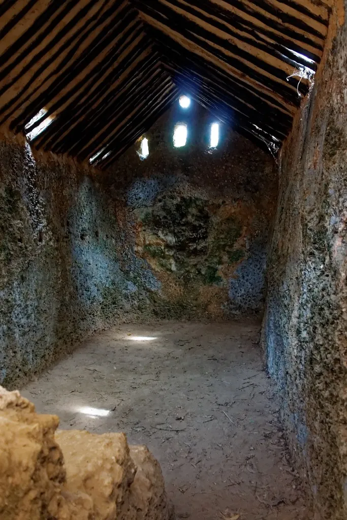 Interior of a narrow stone chamber with light through small roof openings