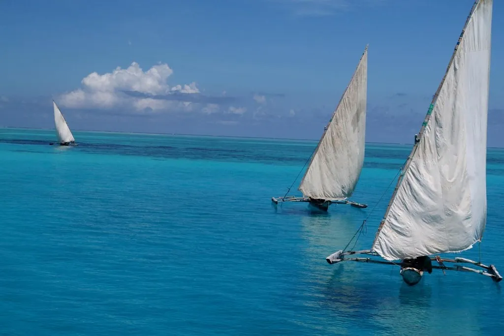 Two outrigger sailing boats with white sails on calm turquoise water