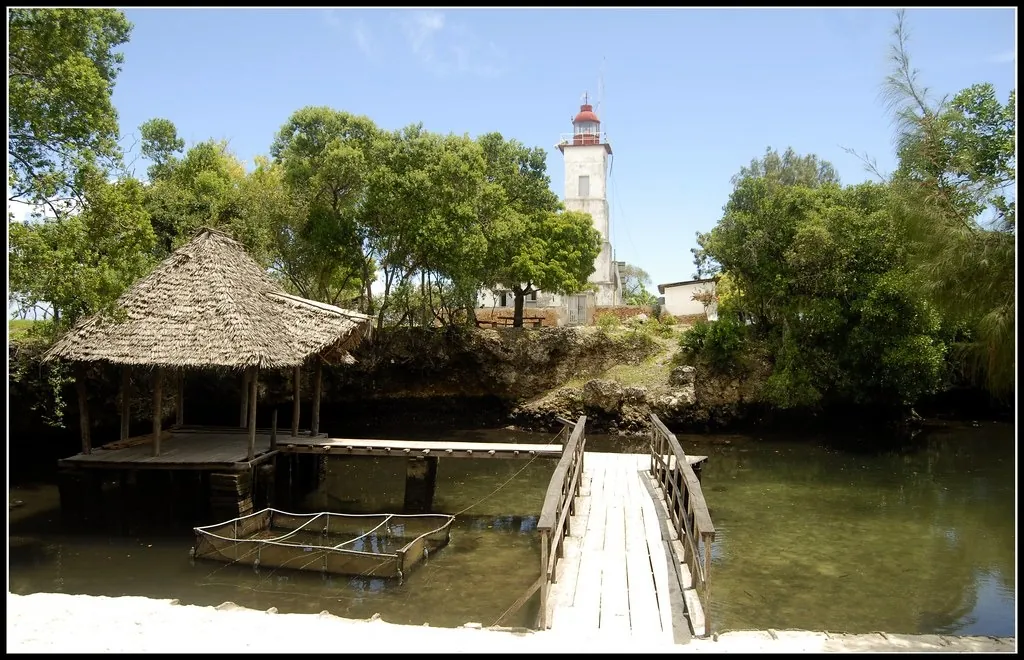 Tidal pool with a thatched shelter, boardwalk, netting pens and the Ras Nungwi lighthouse behind