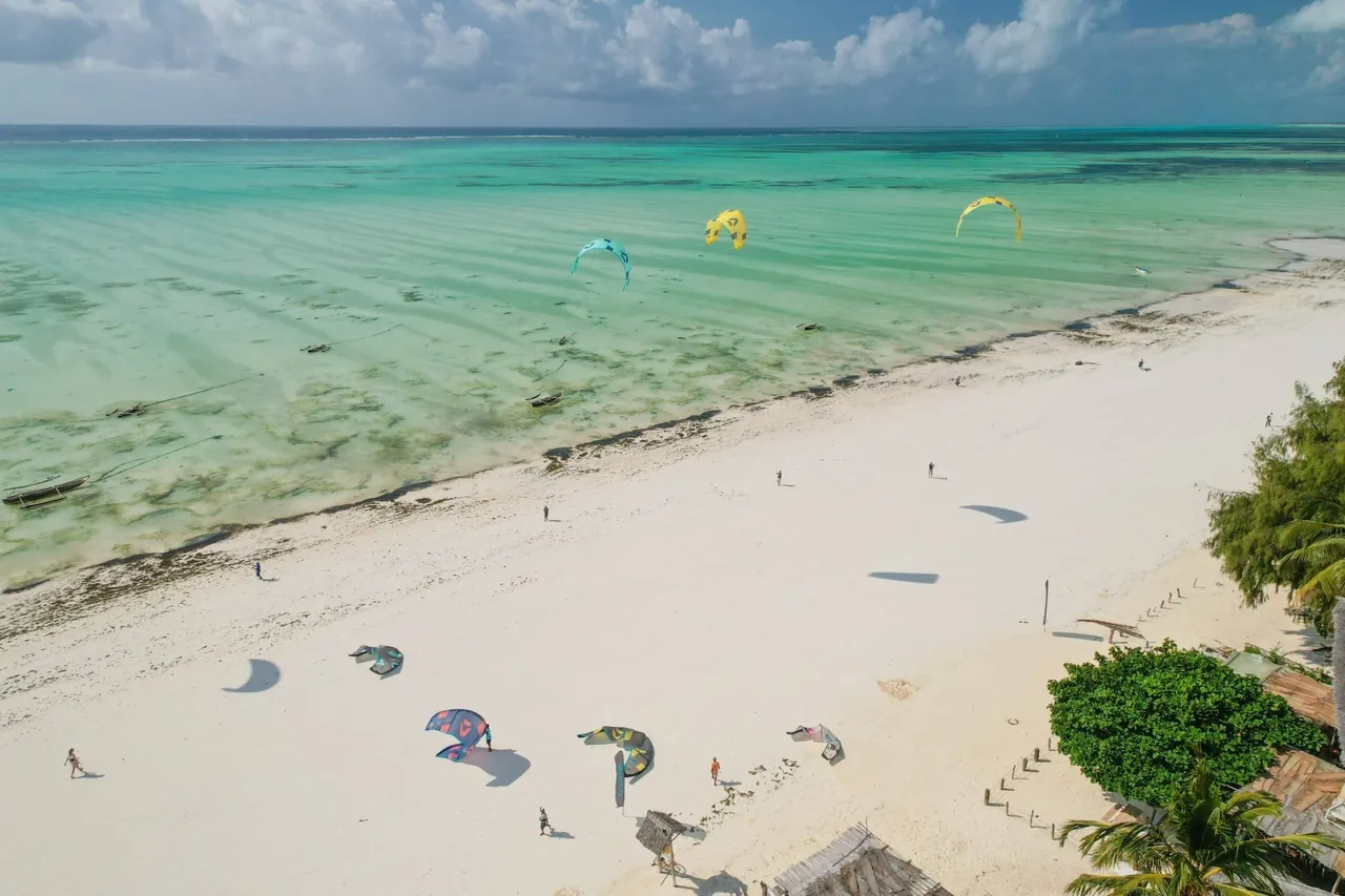 Drone view of the wide, shallow Paje lagoon at mid tide with kites on the beach and in the water