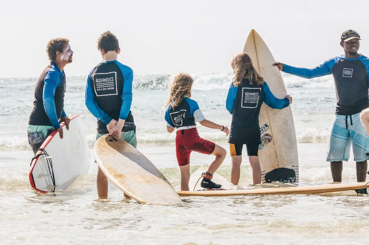 Surf instructors and students with boards standing in shallow white water