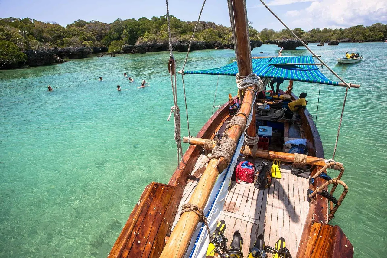 View from a dhow's mast over snorkellers in a turquoise lagoon