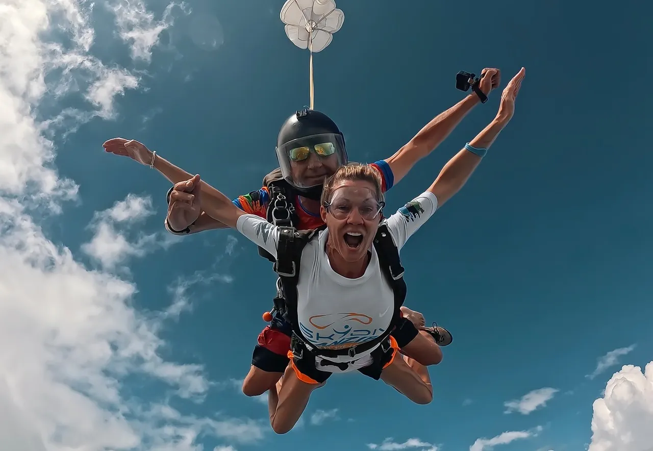 Tandem skydivers in freefall beneath a small drogue parachute