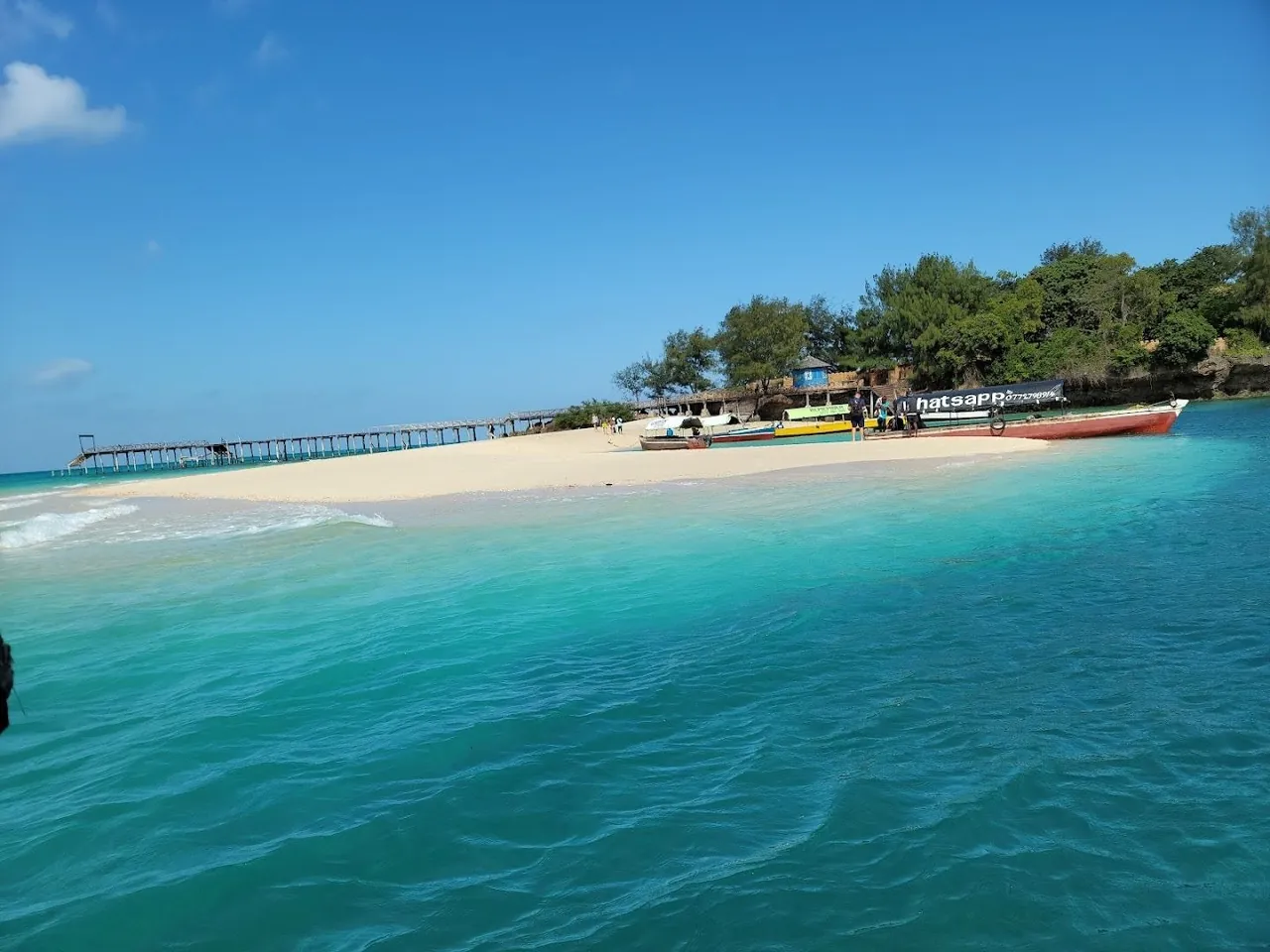 Turquoise water and white beach at Changuu (Prison) Island with a jetty and boats