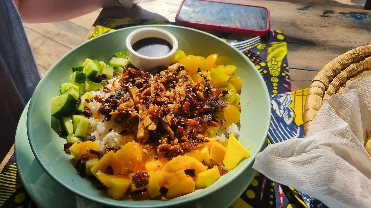 A poke bowl with mango, cucumber and rice on a patterned tablecloth
