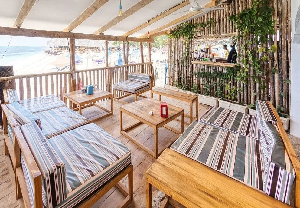 Lounge sofas with striped cushions and low tables on a deck by the beach