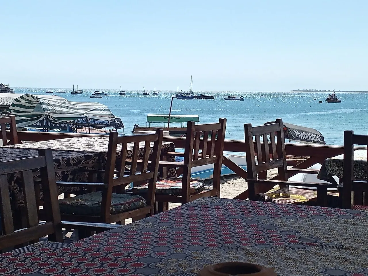 Wooden chairs on a terrace looking over the sea and anchored boats