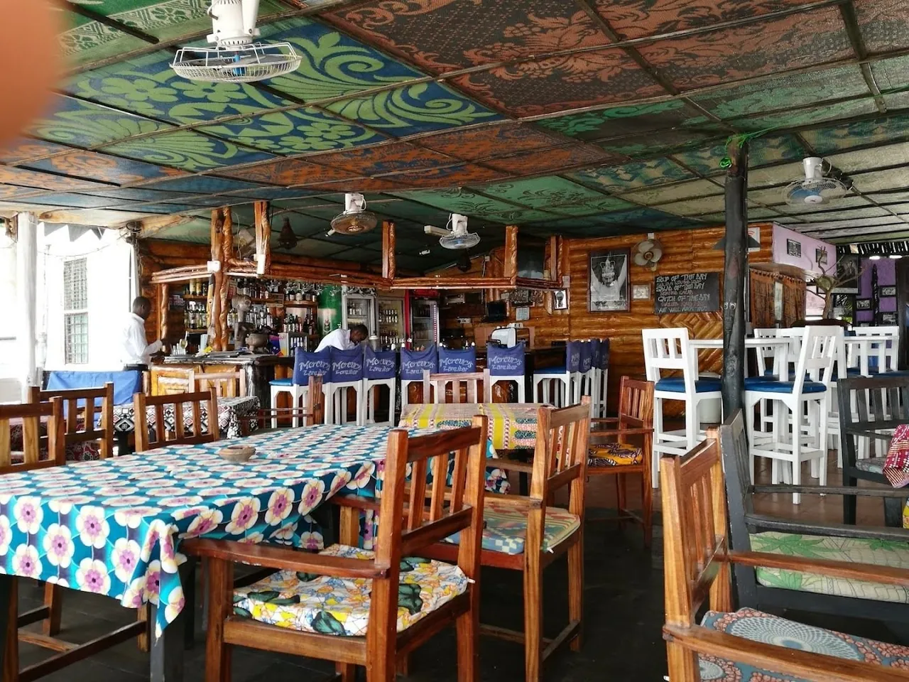 Inside a bar with painted ceiling, check tablecloths and wooden chairs