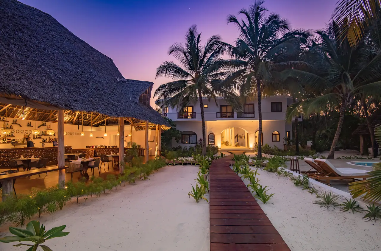 The thatched restaurant lit up at dusk at the end of a garden path