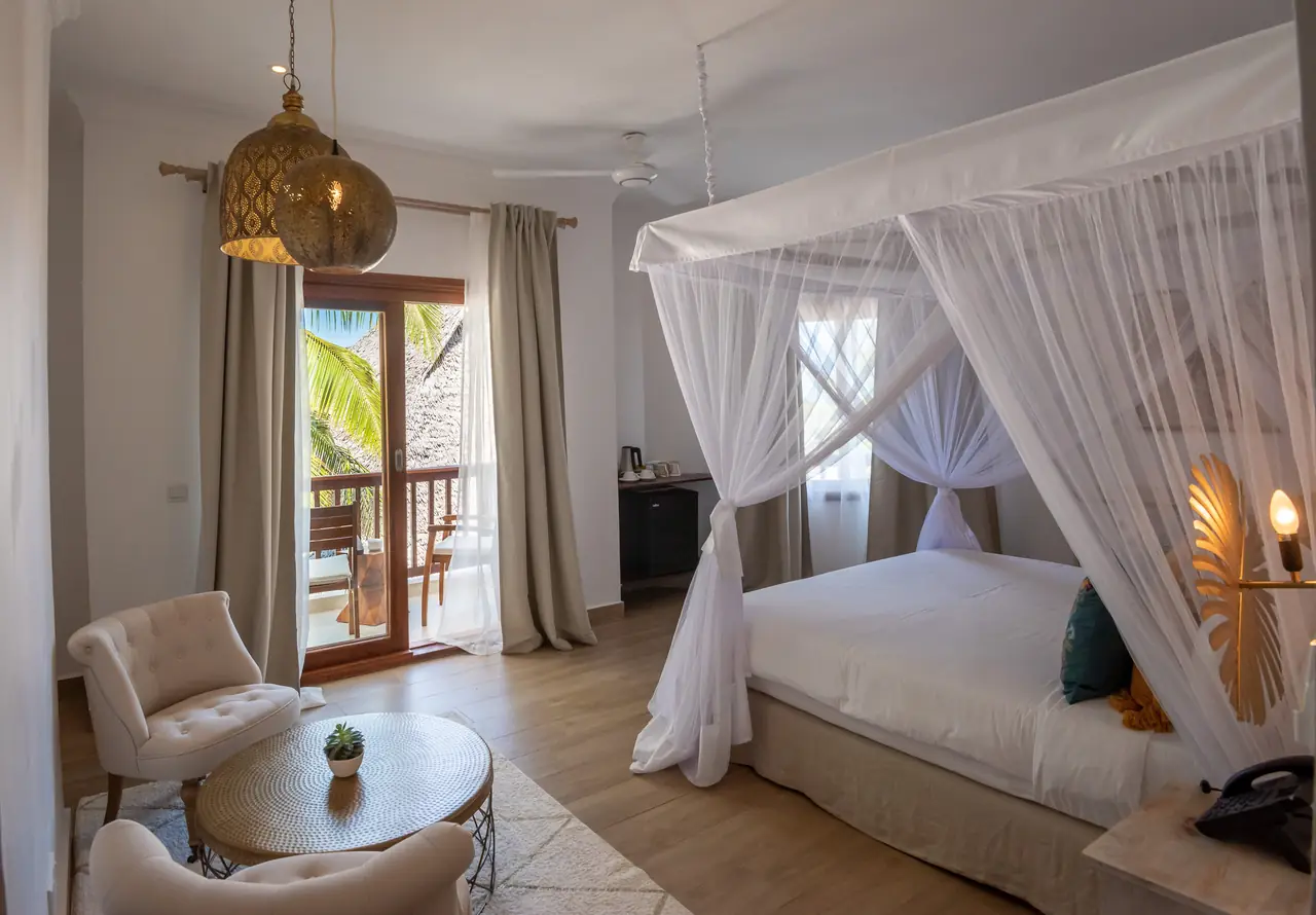 A bedroom with a four-poster bed draped in white netting and a balcony