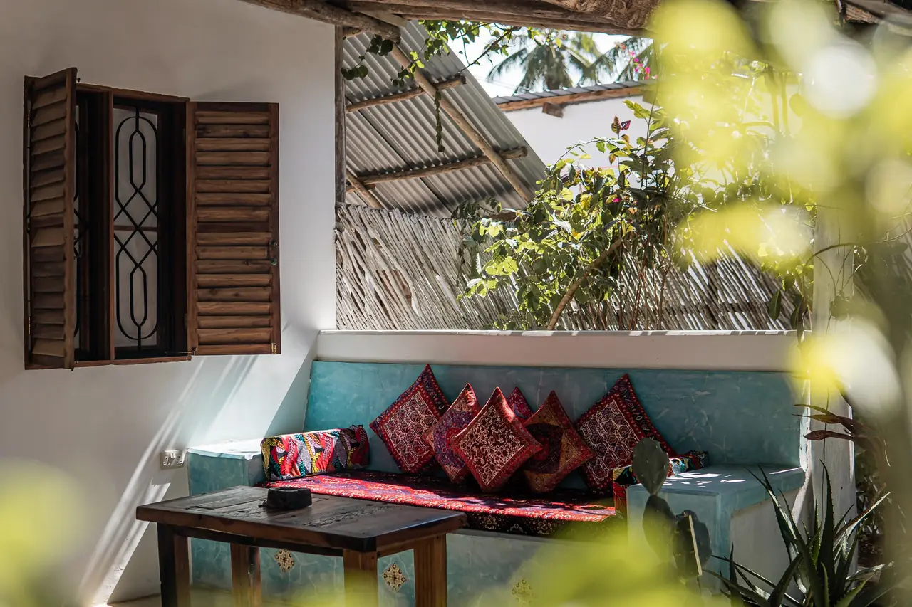 A lounge nook with red cushions under wooden shutters