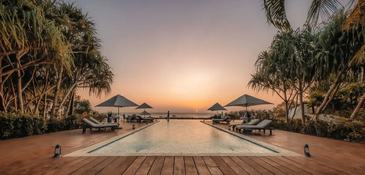 Kilindi's infinity pool and deck at sunset, framed by palms