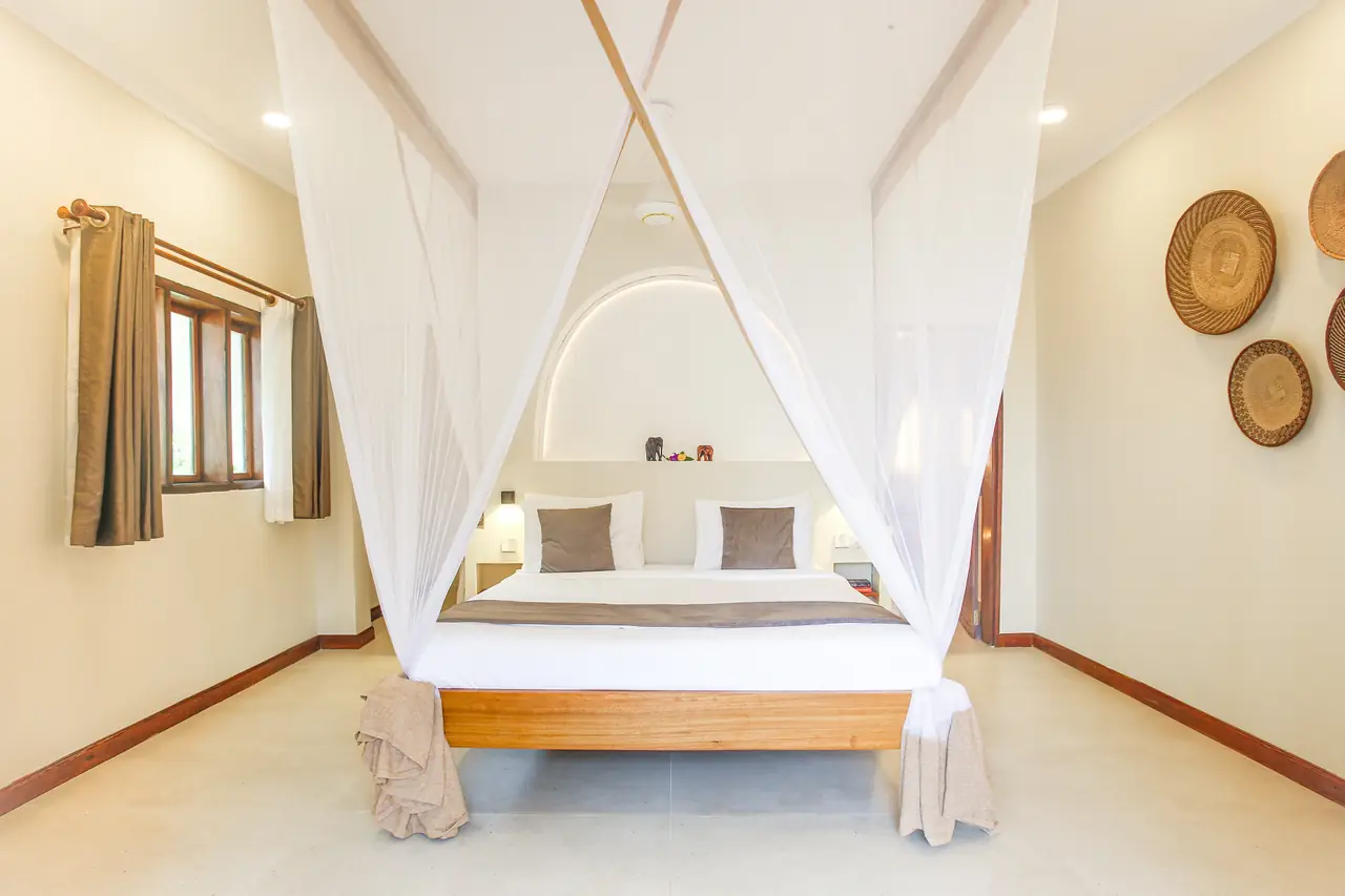A bedroom with a four-poster bed and white nets