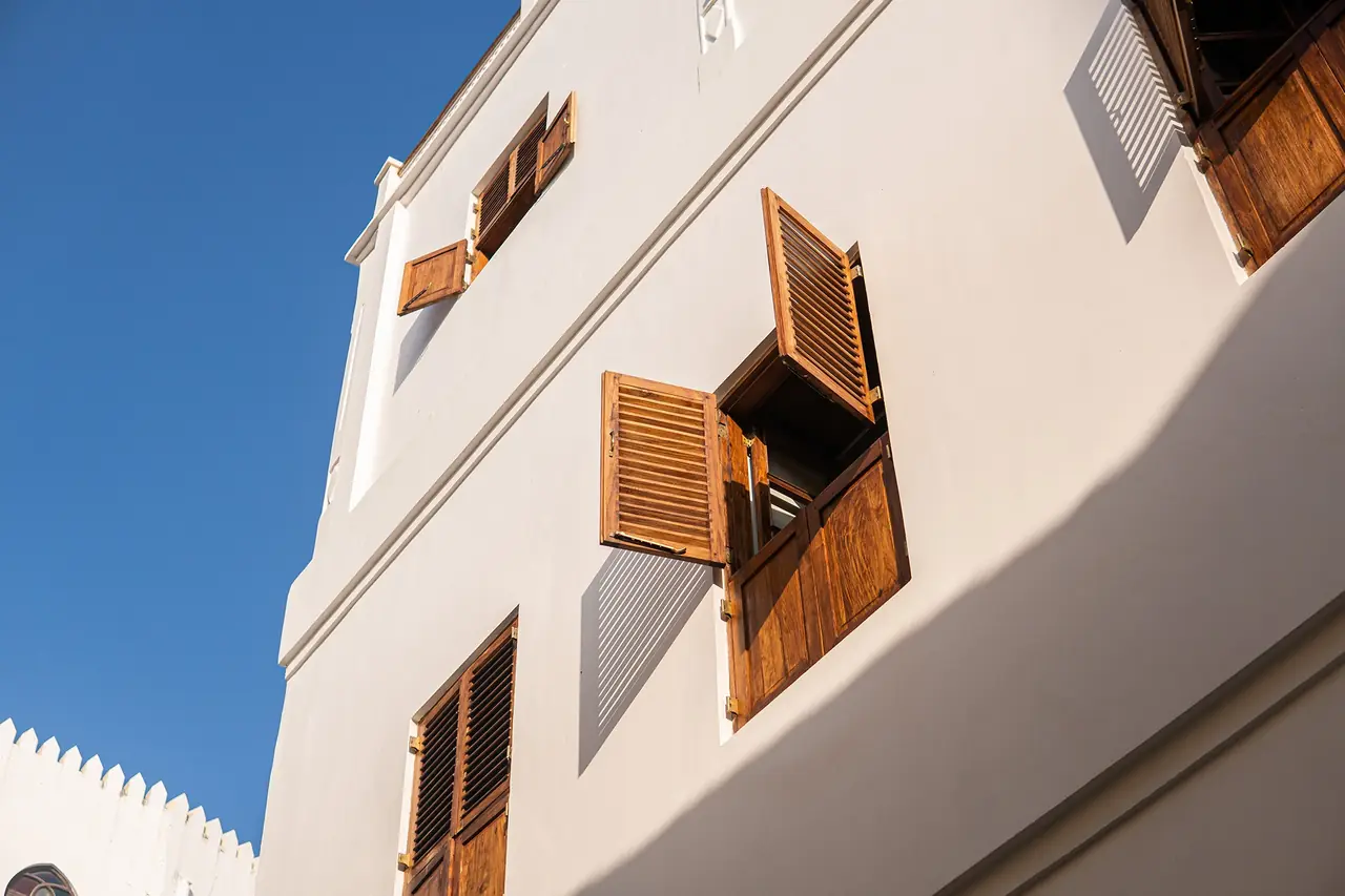 The white facade with wooden shutters against a blue sky
