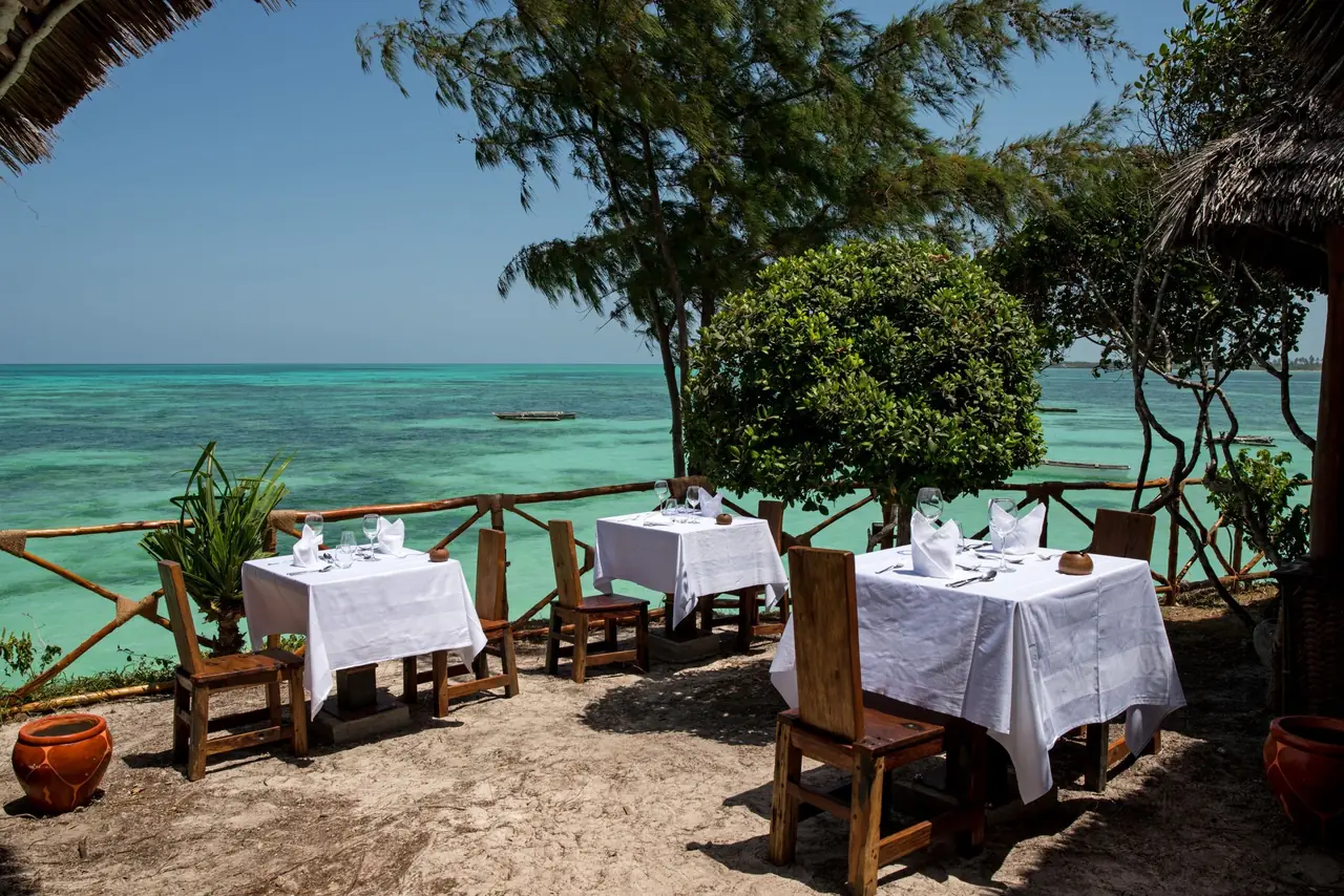 Dining tables with white cloths on a terrace overlooking the sea