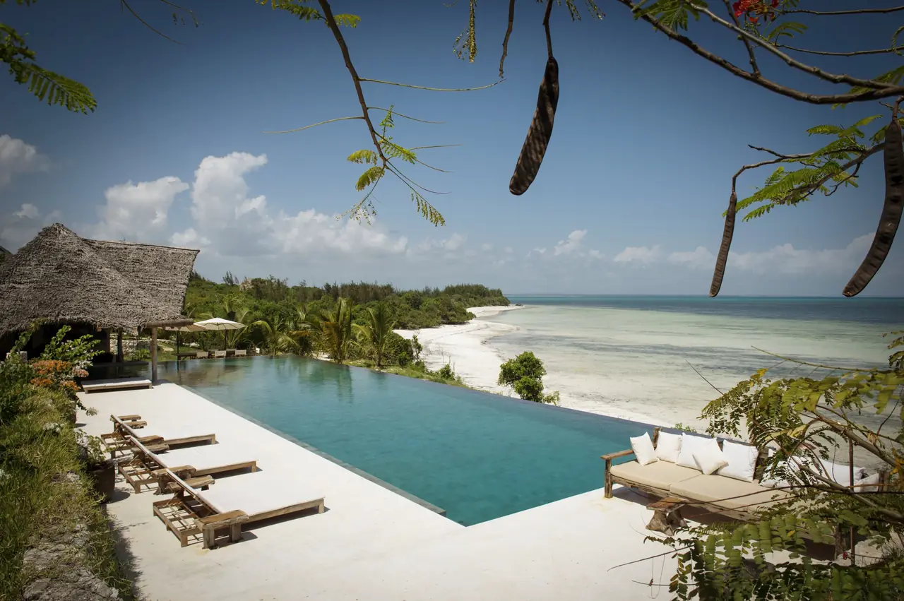 An infinity pool above a white beach and turquoise water