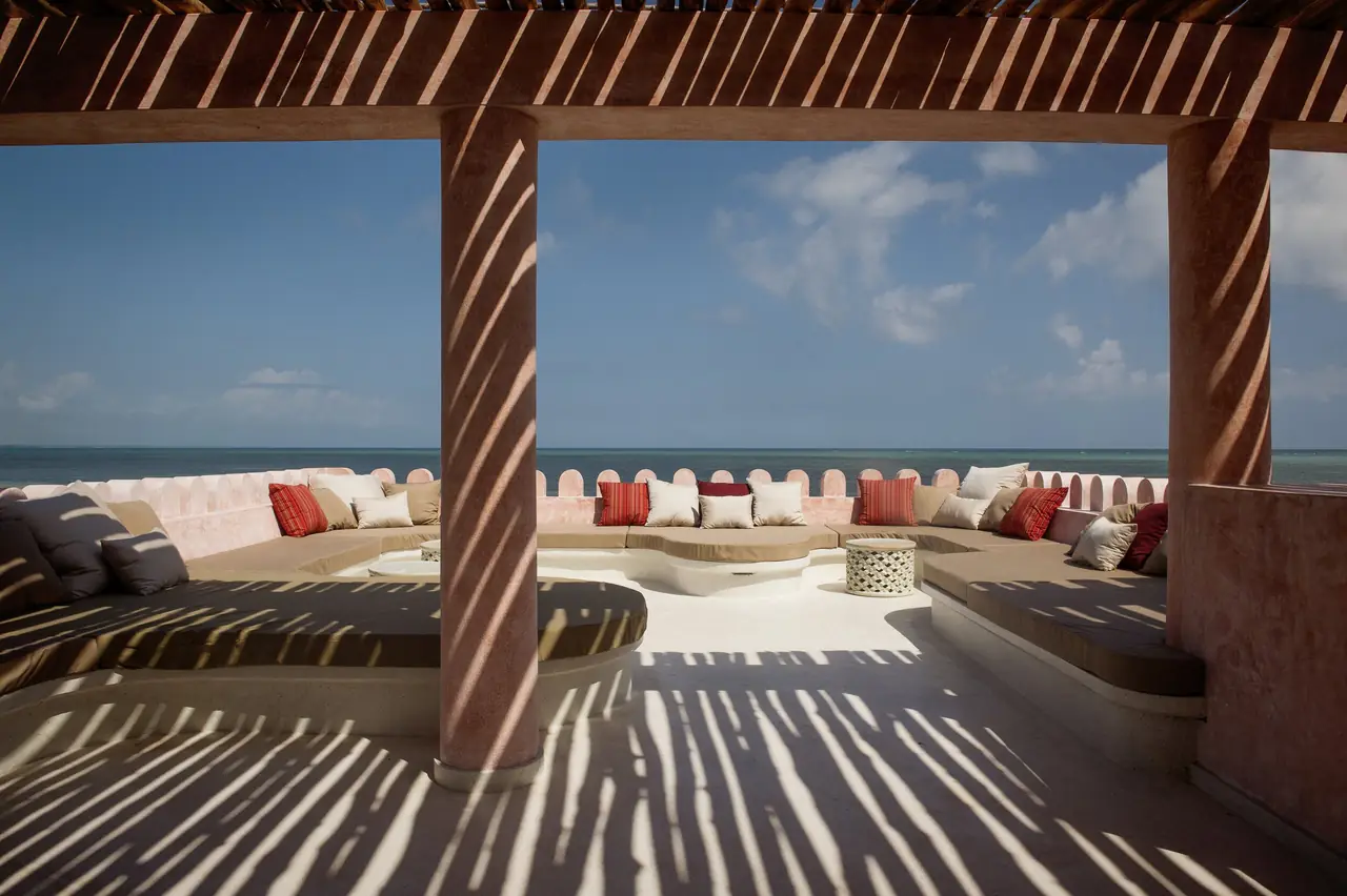 A shaded terrace with cushioned seating looking out to sea