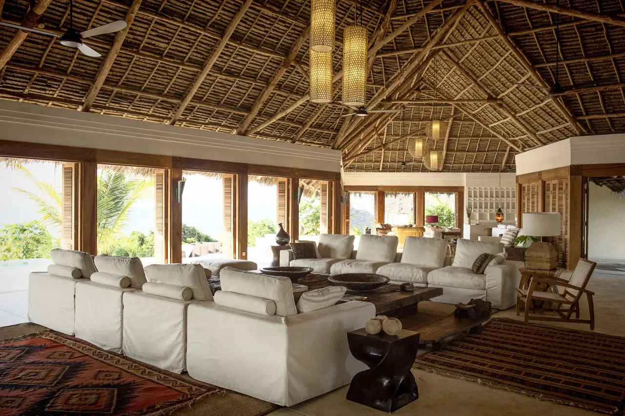 A large lounge with white sofas under a high thatched roof