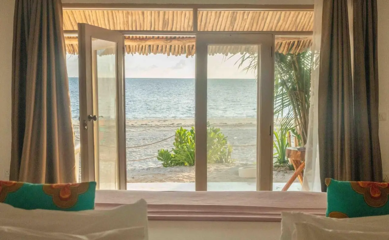 A room with glass doors open to the beach and sea