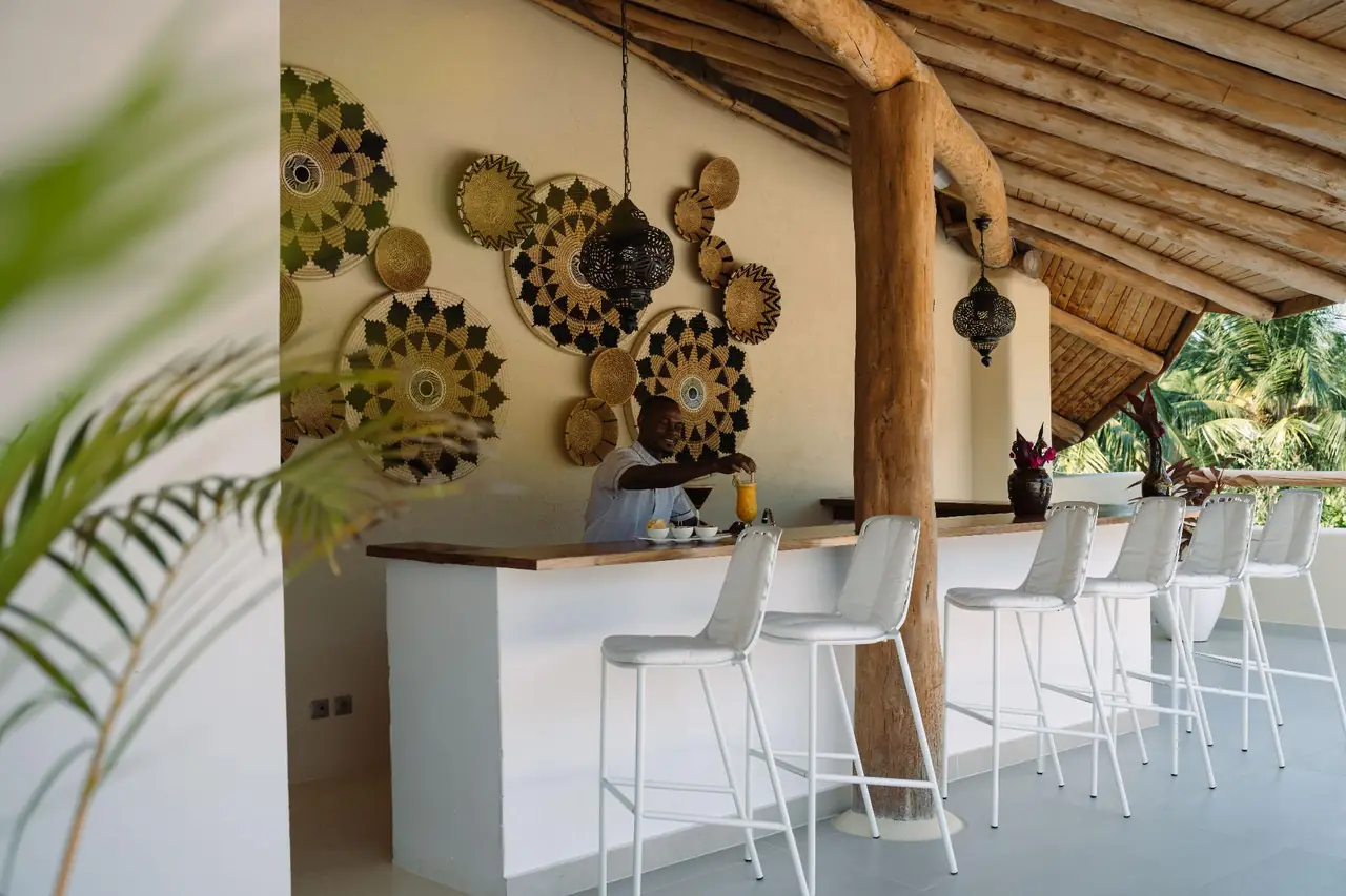 A white bar counter under a timber roof hung with woven baskets