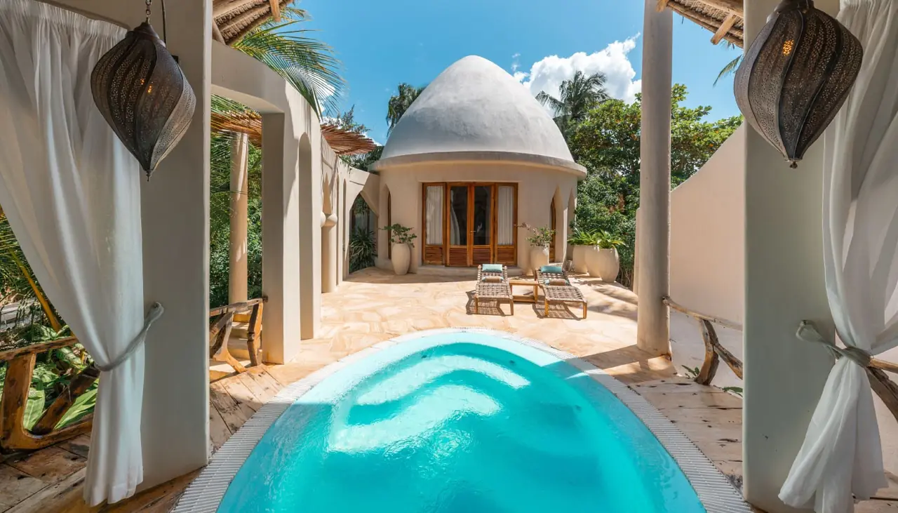 A plunge pool leading between white columns to a domed villa