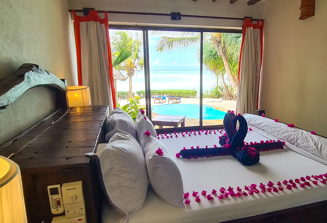 A bed decorated with petals, with the pool and sea through the window