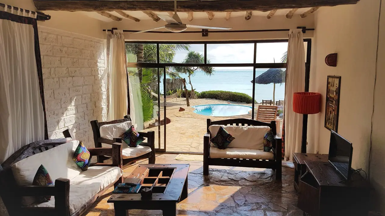 A suite lounge with wooden furniture opening onto a terrace and pool