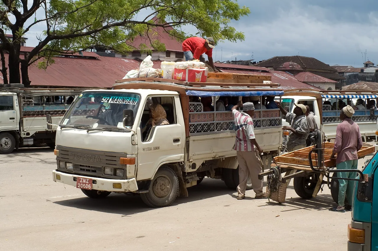 Truck dala dala being loaded with goods on the roof beside other dala dalas