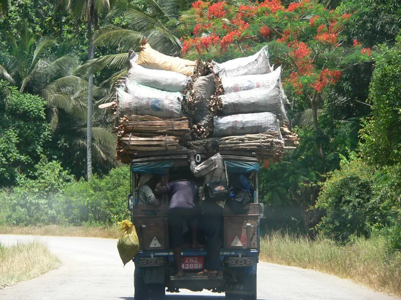Dala dala truck piled high with sacks and passengers hanging on the back