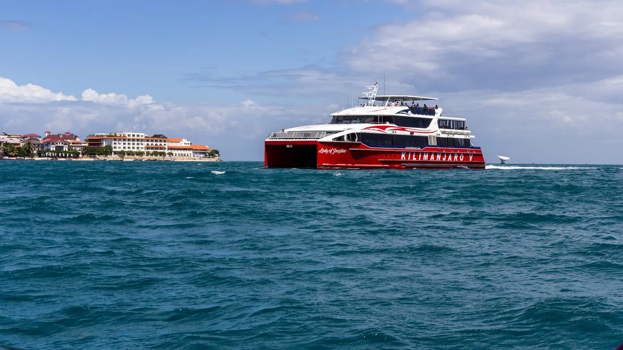 Red Azam Marine catamaran Kilimanjaro V crossing choppy water towards the Stone Town waterfront