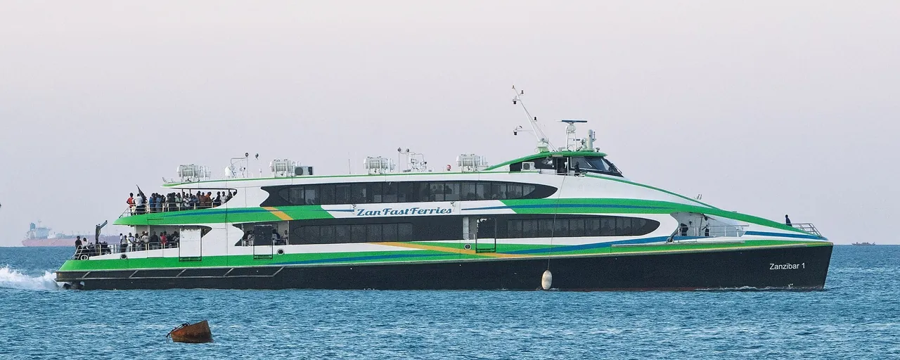 Green-and-white Zan Fast Ferries catamaran Zanzibar 1 with passengers on its open rear deck