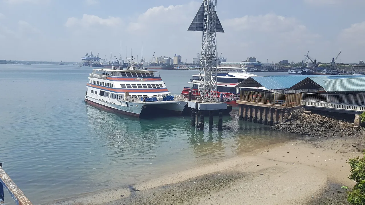 Ferries moored at a jetty in Dar es Salaam harbour at low tide, with port cranes behind