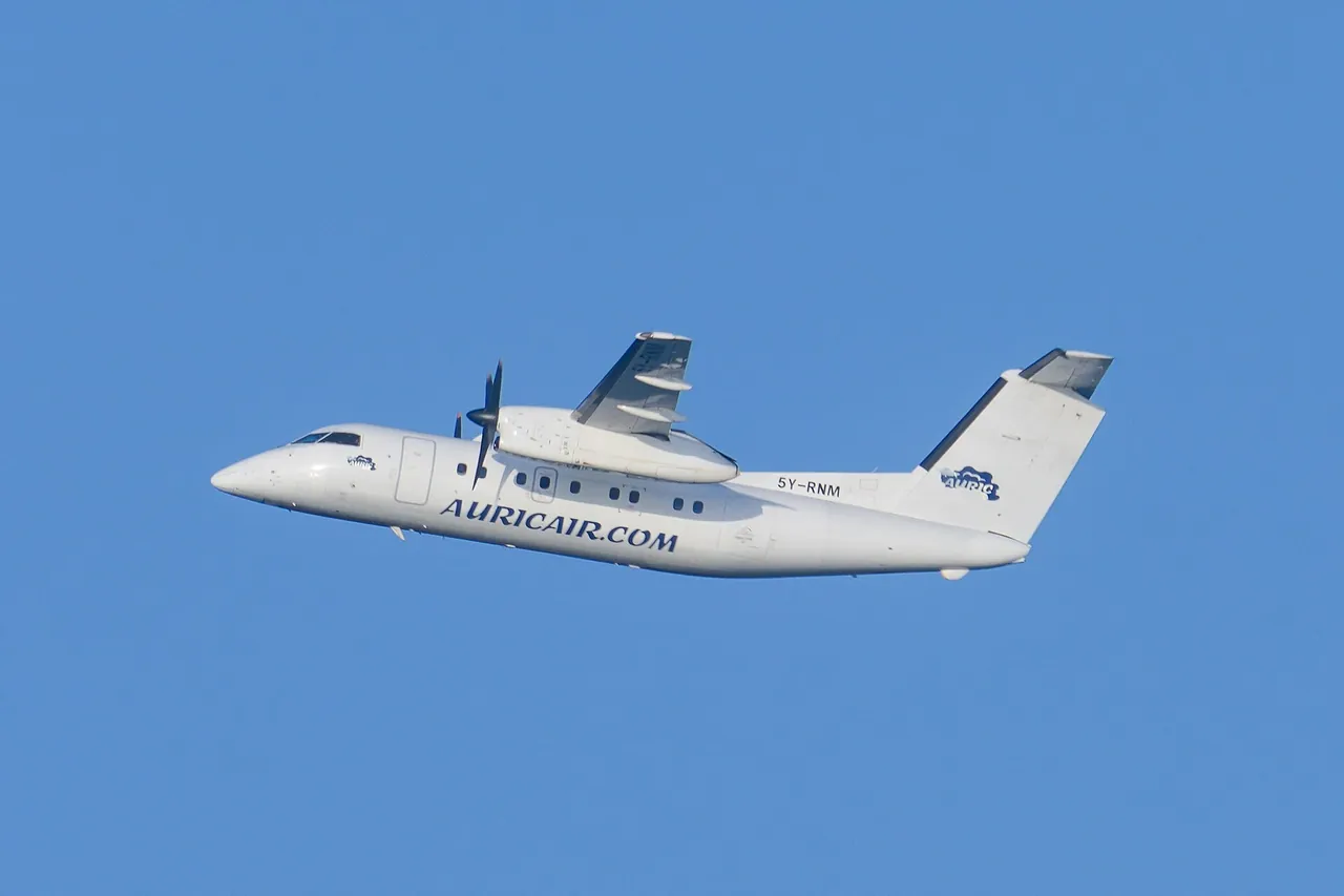White Auric Air Dash 8 turboprop, registration 5Y-RNM, climbing against a blue sky