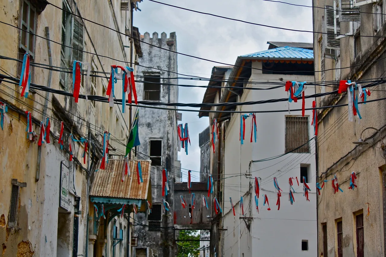 A Stone Town street hung with red, white and blue ribbon bunting between old buildings and a crenellated tower