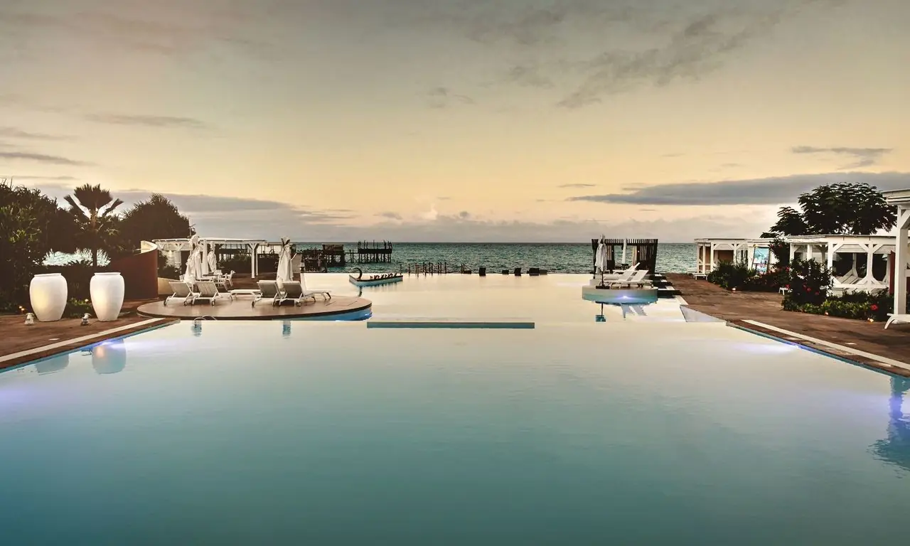 A wide infinity pool merging with the sea at dusk