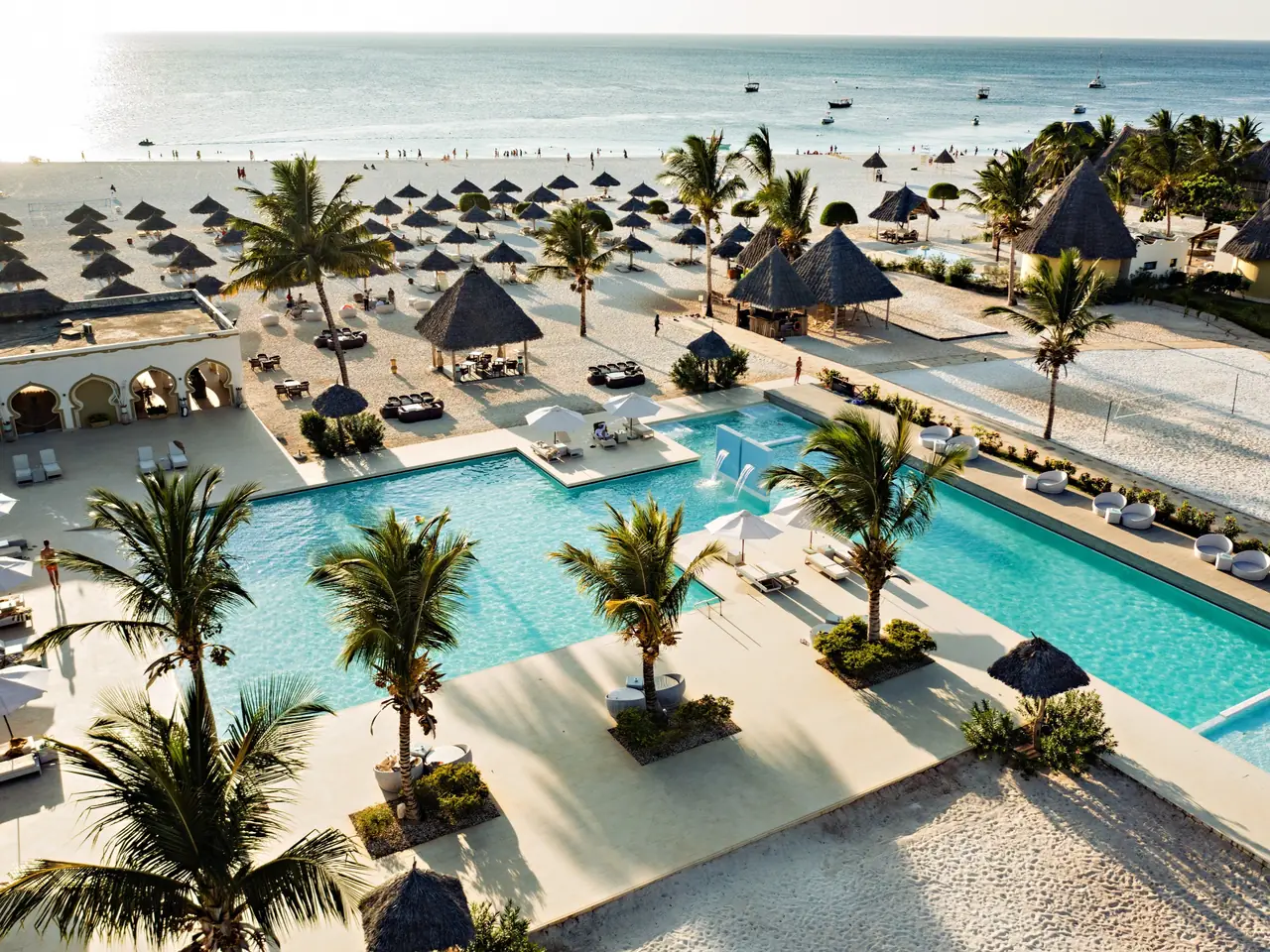 Aerial view of the resort's pools, palms and thatched umbrellas above Kendwa beach