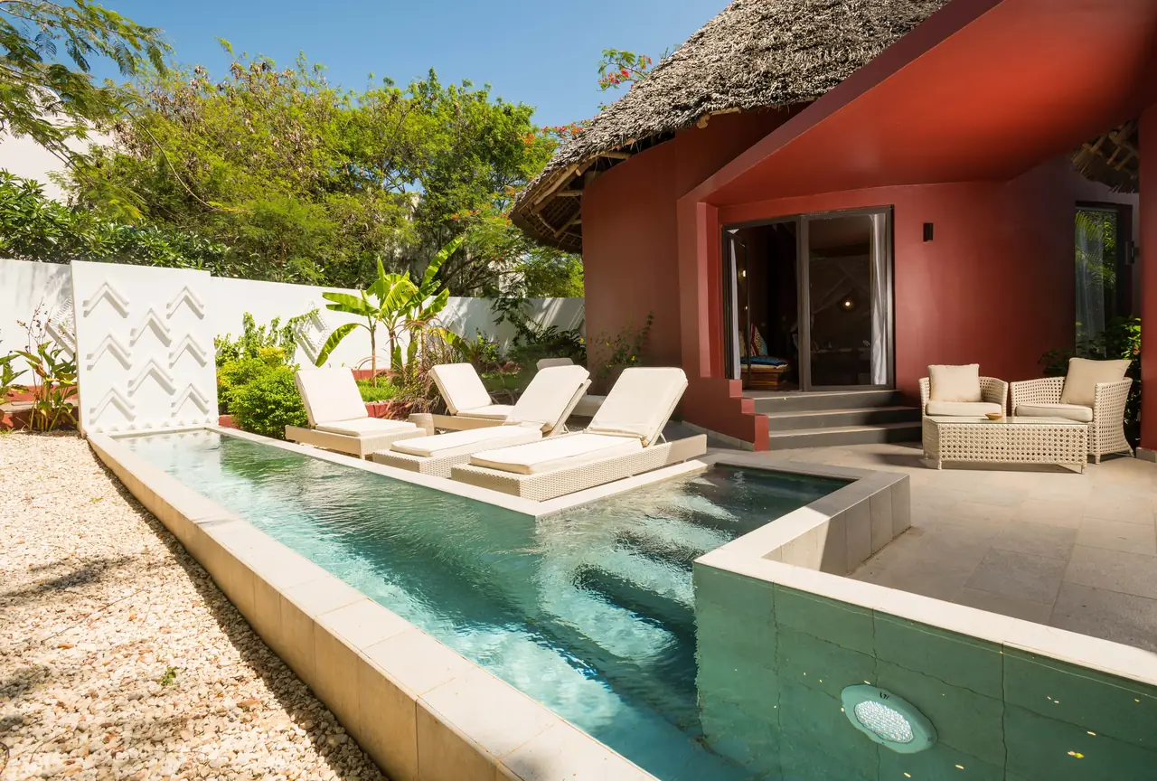 A red-walled villa with a long private pool and loungers