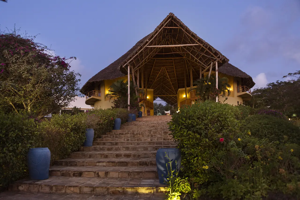 Lit stone steps leading up to a thatched building at dusk