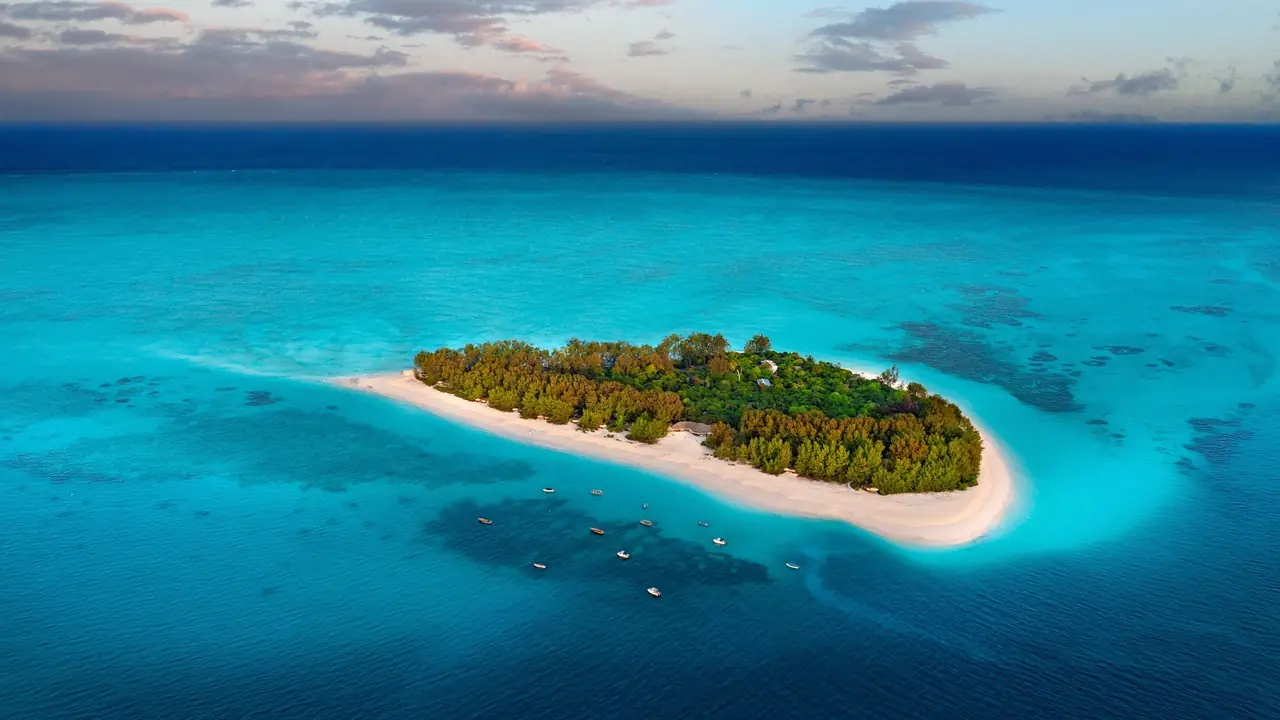 Aerial view of Mnemba, a small forested island ringed by white sand and turquoise reef