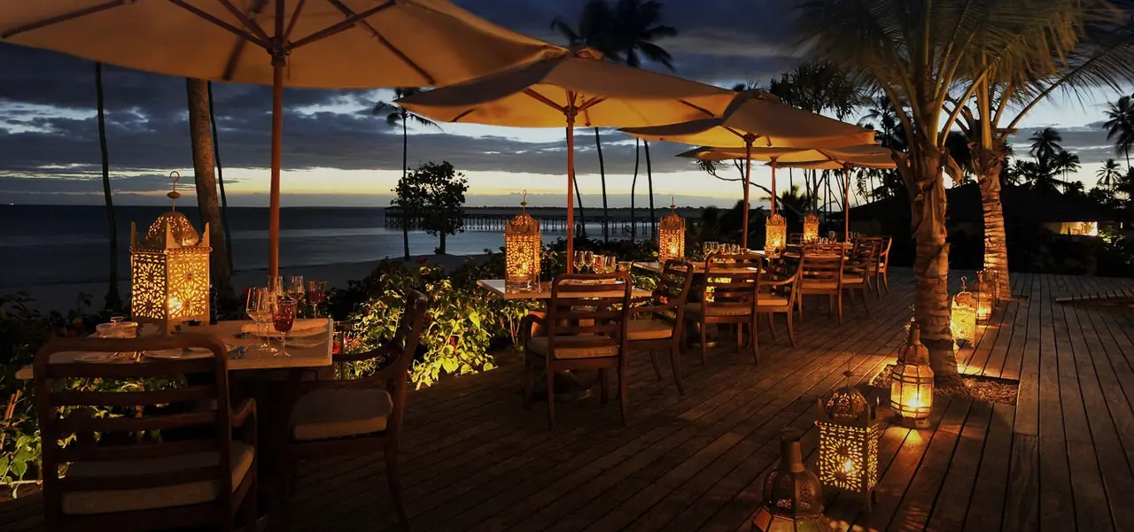 A candlelit terrace restaurant above the sea at dusk