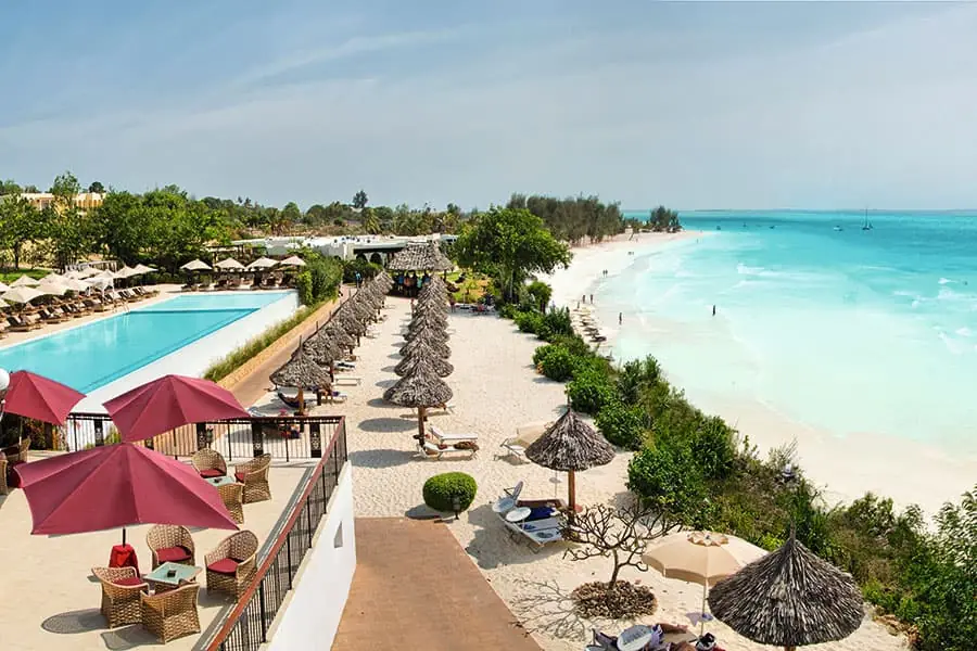 A pool terrace with red umbrellas above the beach