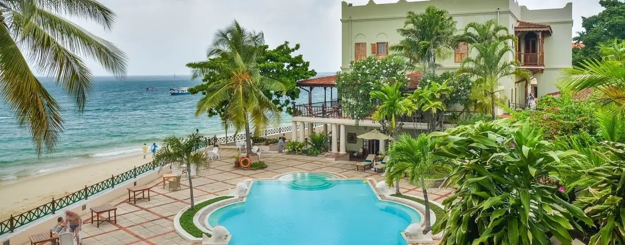 A pool in a palm garden in front of the historic hotel building on the Stone Town seafront