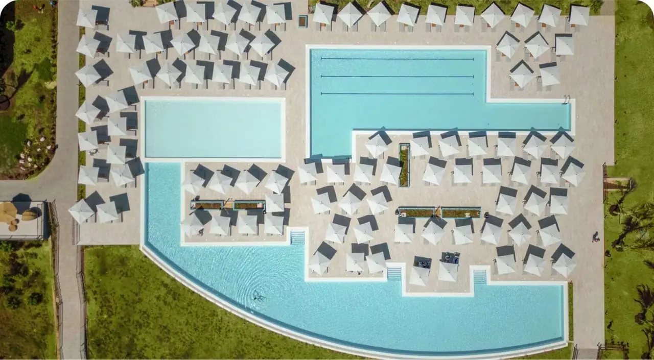 Aerial view of a large curving pool lined with loungers and umbrellas