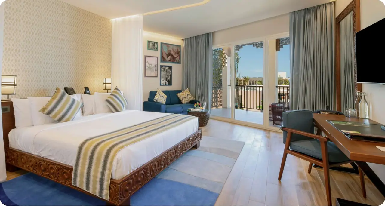 A suite bedroom with a patterned bedspread and a balcony door