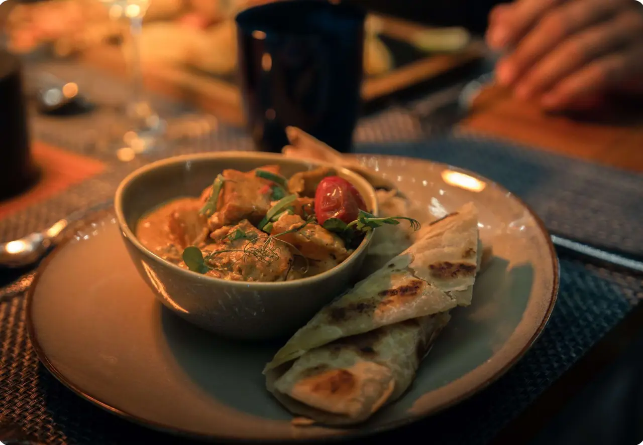 A curry and flatbread served at a candlelit table