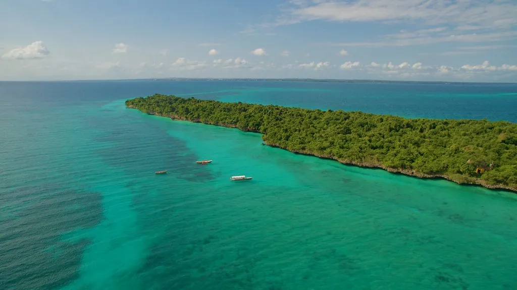 Aerial view of the long, forested Chumbe Island surrounded by turquoise shallow reef