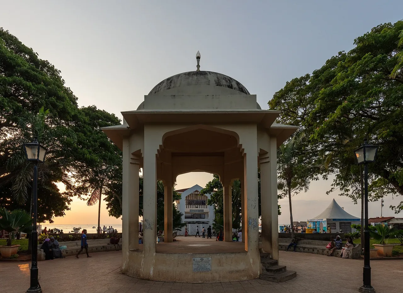 The domed stone gazebo in Forodhani Gardens at dusk, framed by trees and lamp posts