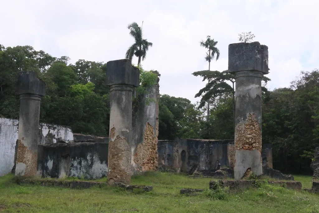 Ruined columns and roofless walls on a lawn under an overcast sky