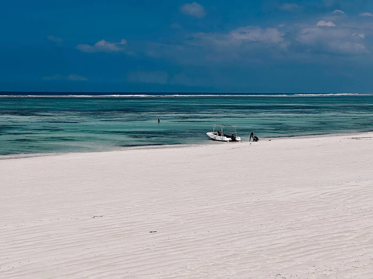 White sand beach with turquoise and deep blue water stretching to the horizon